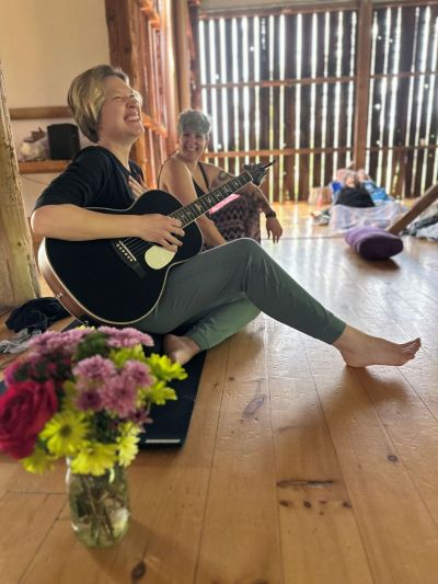 A person playing a guitar in the Roots and River yoga studio in Brunswick, MD.